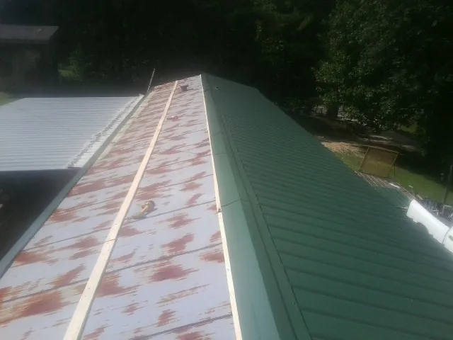 Old rusted panels beside newly installed green metal roofing — Wind Damage Roof Repair by Roofing Brothers in White Lake