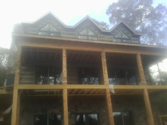 Dormers and porch framing on a large log home under construction — Roof Coating work by our crew in White Lake