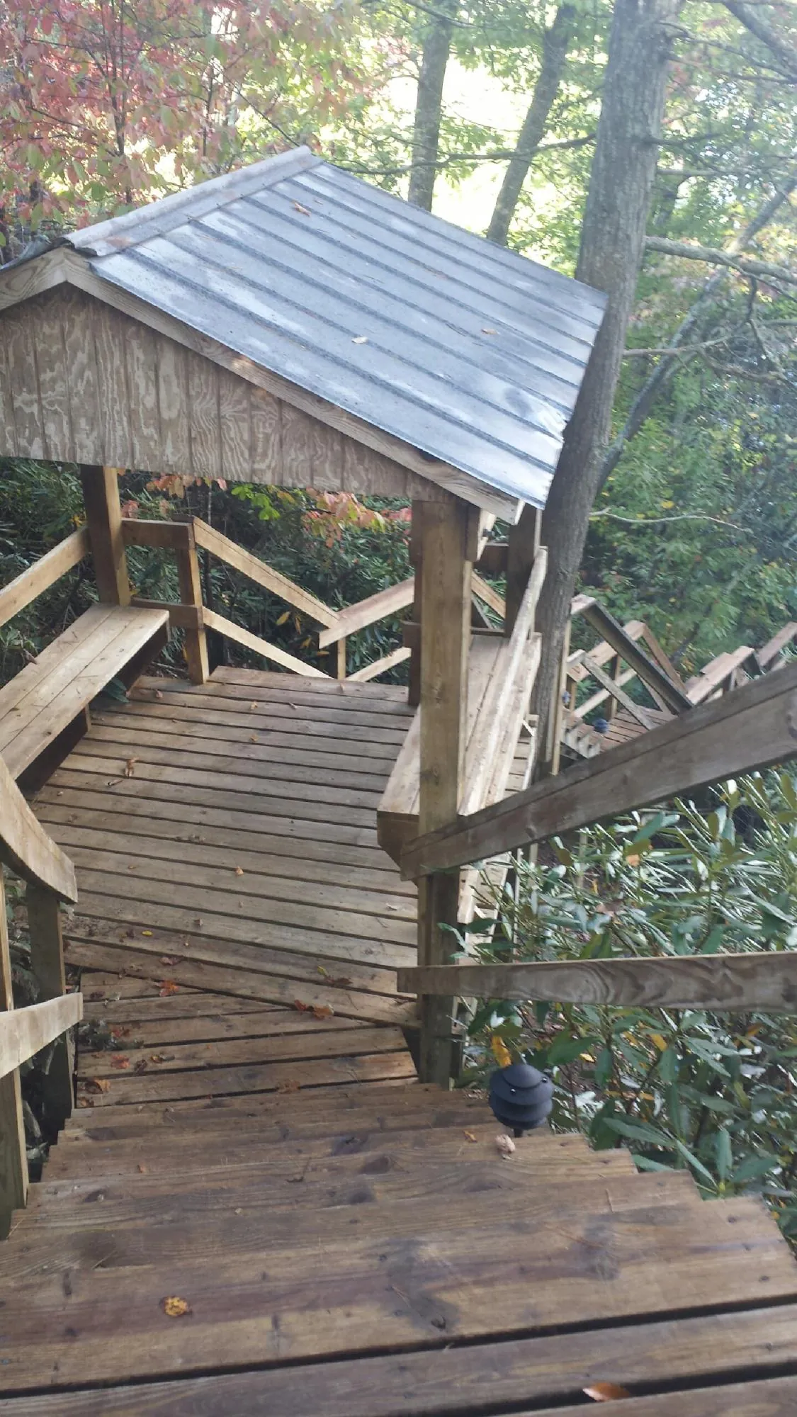 Metal roofed shelter over wooden steps on a wooded walkway — Skylight Repair & Installation work by our crew in White Lake